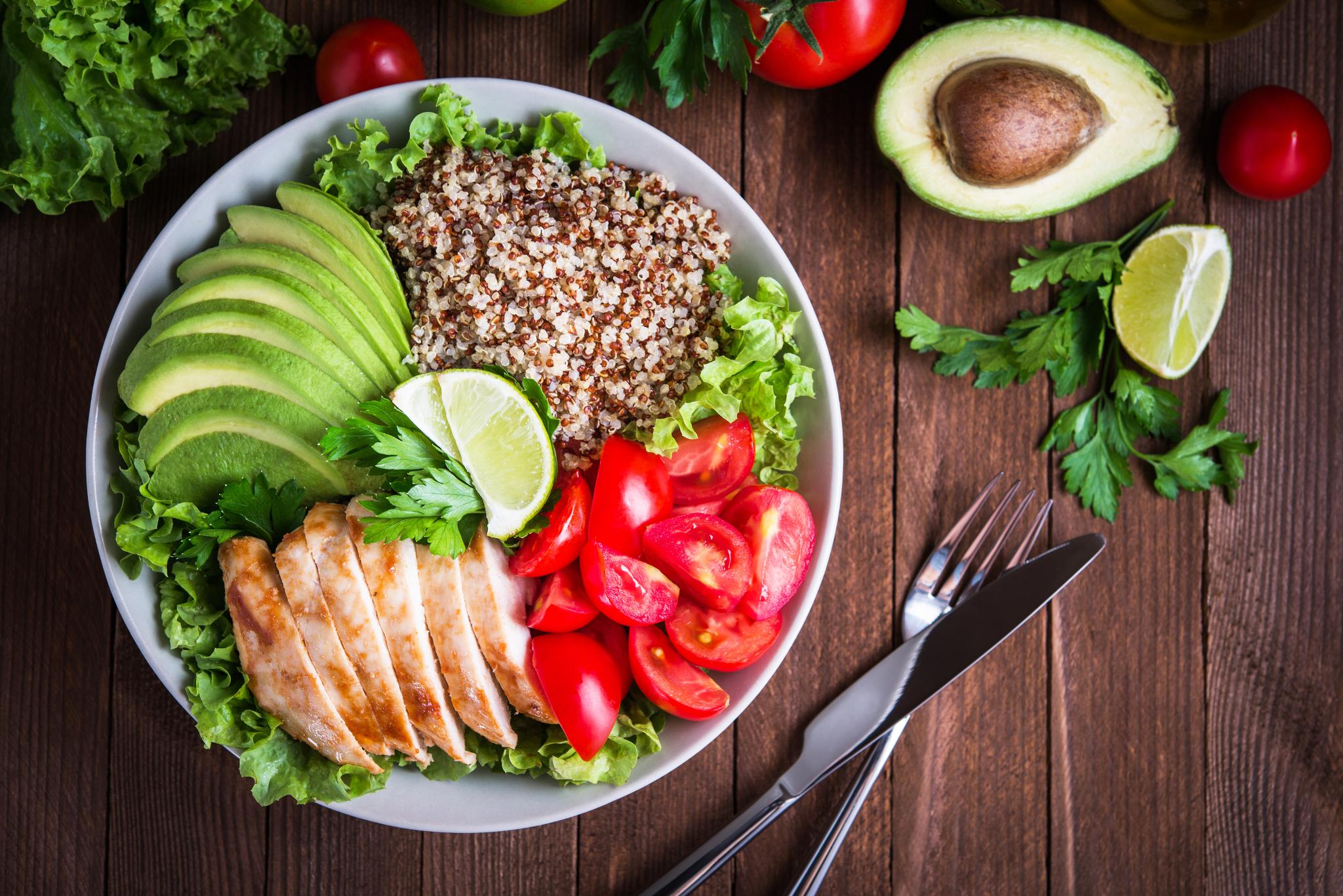 Healthy plate image of plate with chicken breast, Avacado, Cherry tomatoes, lime wedges and quinoa